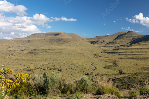 A mountain landscape in the Mountain Zebra national Park near Cradock in South Africa. Green hills with a valley leading to a blue sky with some white clouds