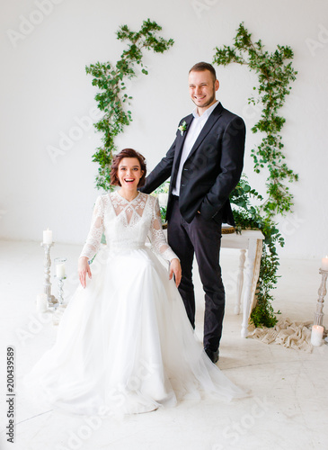 Wedding couple groom and bride posing in a white Studio. Black suit and dress.