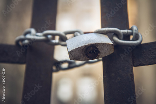 Abandoned tenant house, with a gate closed with a padlock in the foreground - focus on the padlock