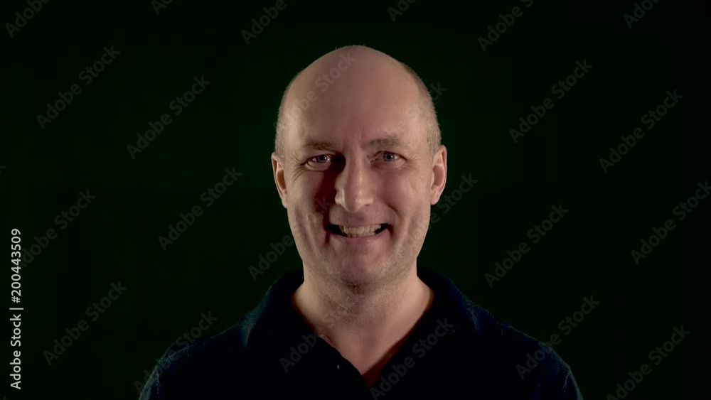 Laughing middle aged man looking at camera. Low key close up shot. Laughing middle aged man looking at camera. Low key close up shot.