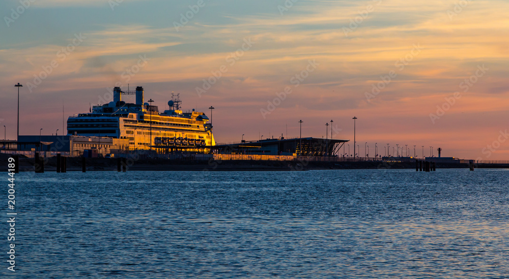 The cruise ship is at the pier in the rays of the setting sun