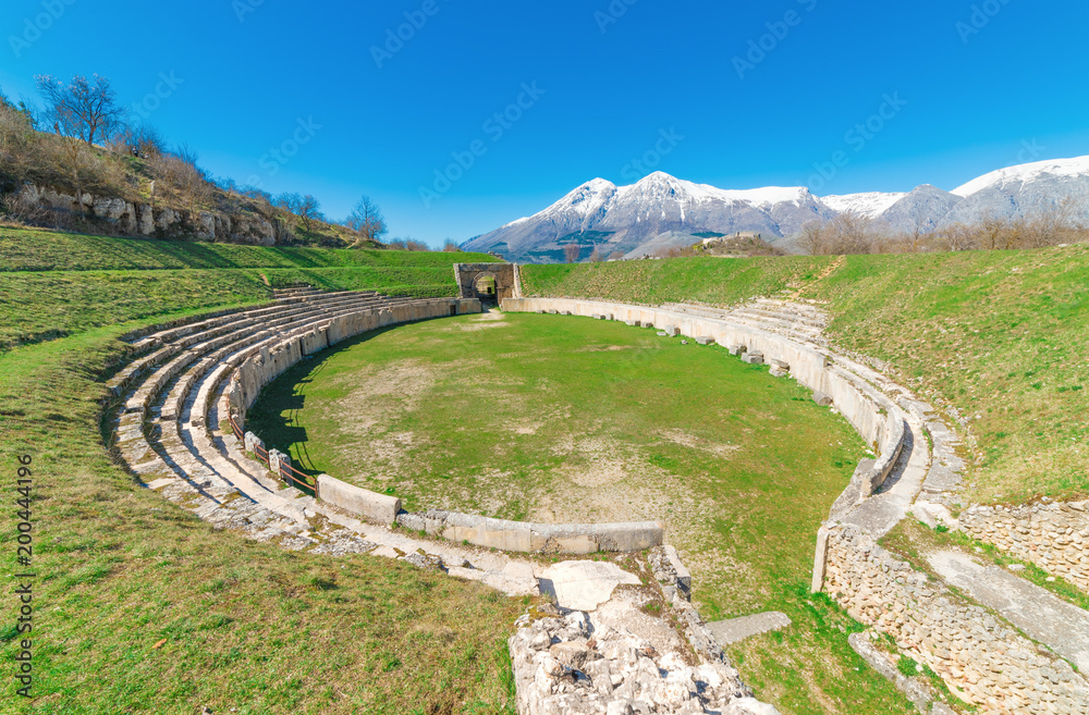 Alba Fucens (Italy) - An evocative Roman archaeological site with amphitheater, in a public park in front of Monte Velino mountain with snow, Abruzzo region, central Italy