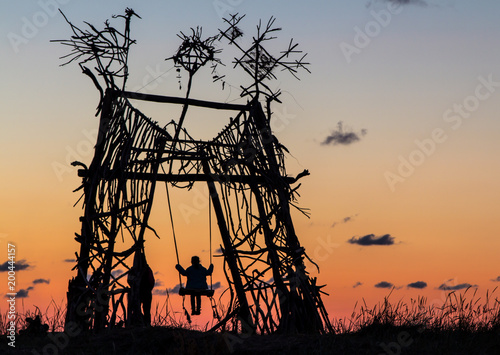 Young girl swinging on a unique swing at sunset