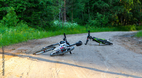 Two bicycles lie on a forest dirt road