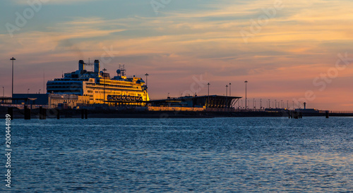 The cruise ship is at the pier in the rays of the setting sun