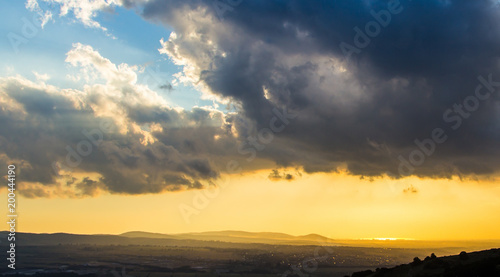 A large storm cloud over the city at sunset