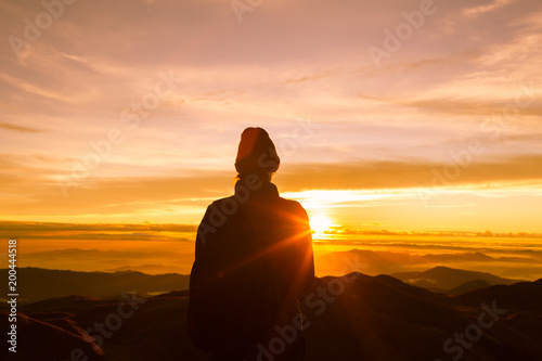 woman reaching the top of the mountain to see the golden sunset.  © kieferpix