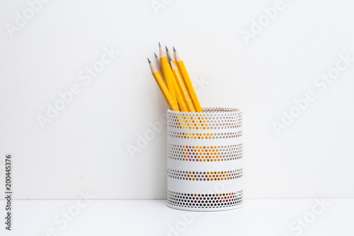 Yellow pencils in white metal pot on a white background