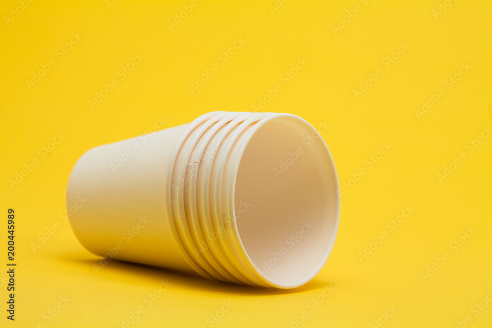White paper cup on yellow background 