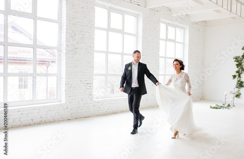 Bride and groom standing on white wall background