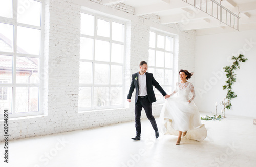 Bride and groom standing on white wall background