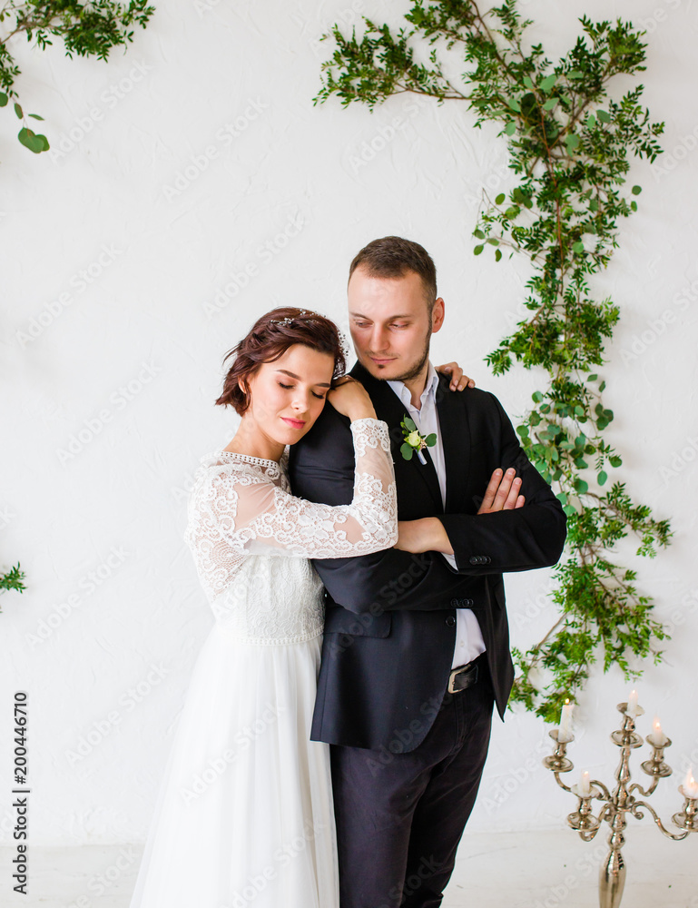 Bride and groom standing on white wall background 스톡 사진 | Adobe Stock