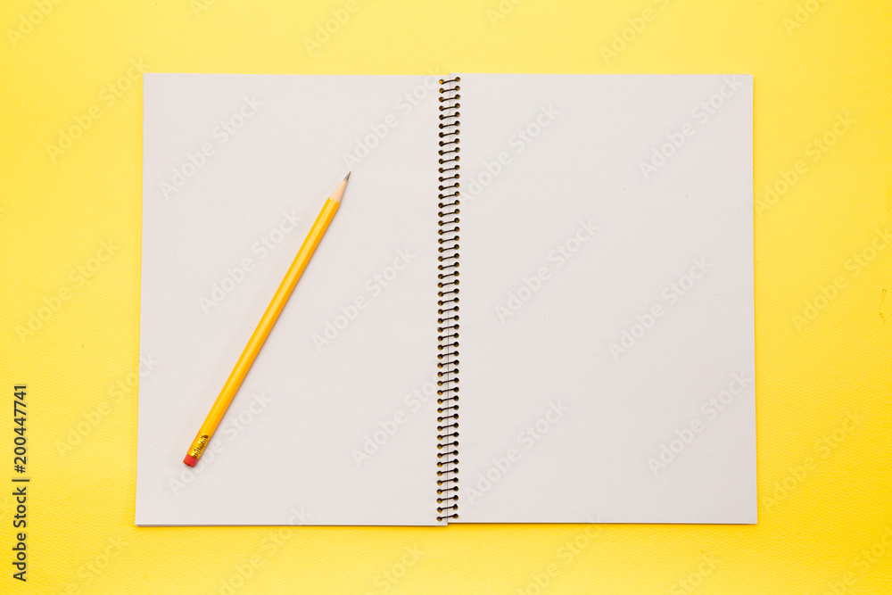 Open note book blank pages with yellow pencil on yellow background Open note book blank pages with yellow pencil on yellow background