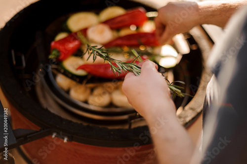 Man hands cooking vegetables on grill and adding rosemary into a dish © fesenko