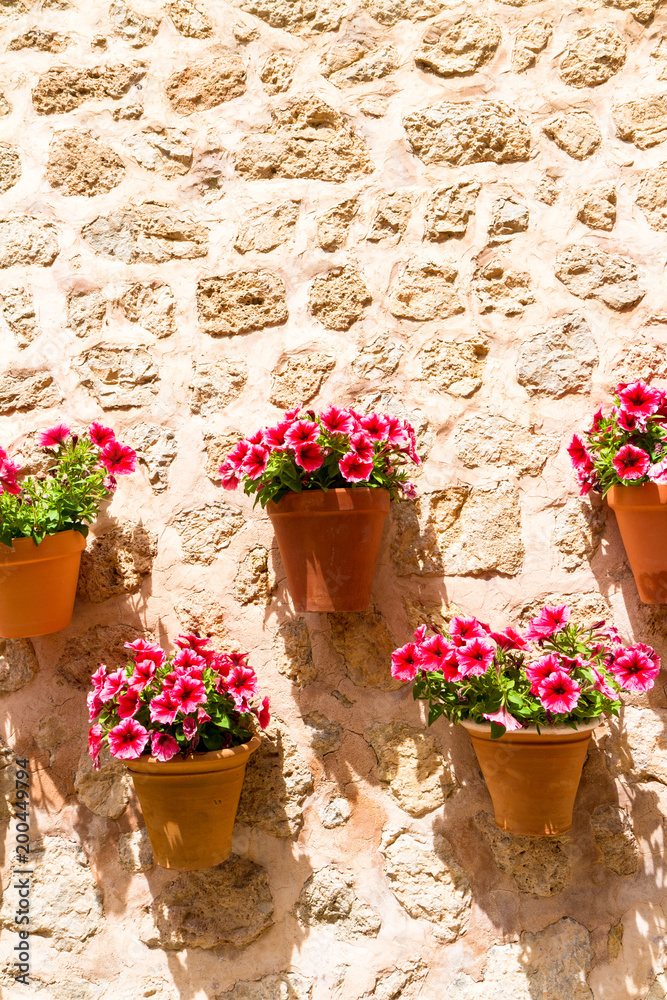 Typical exterior stone wall decorated with hanging ceramic flower pots in Valdemossa medieval village, Mallorca, Balearic Islands, Spain