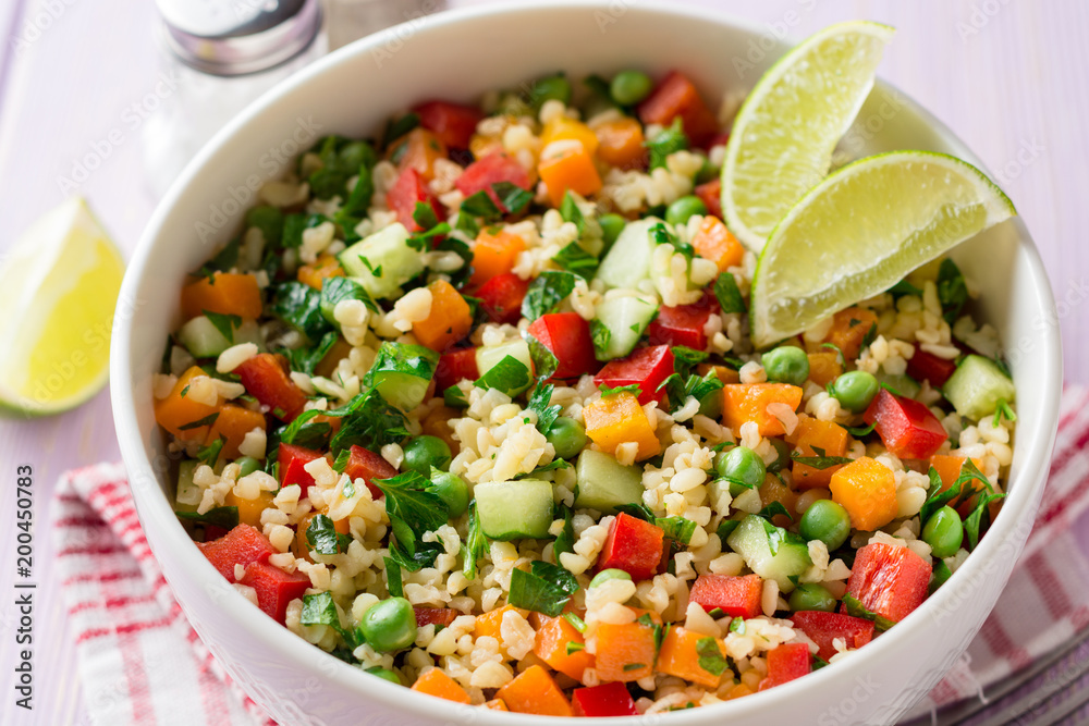 Fresh salad with bulgur and vegetables in bowl on wooden table