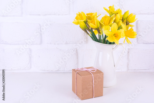 Fototapeta Naklejka Na Ścianę i Meble -  Jar with narcissuses and a gift box at the white background. Spring, mothers day and easter concept