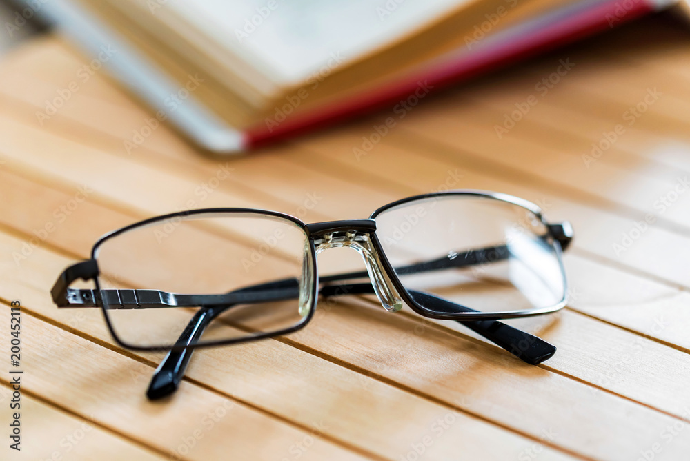 Open book and glasses on wooden table close Open book and glasses on wooden table close