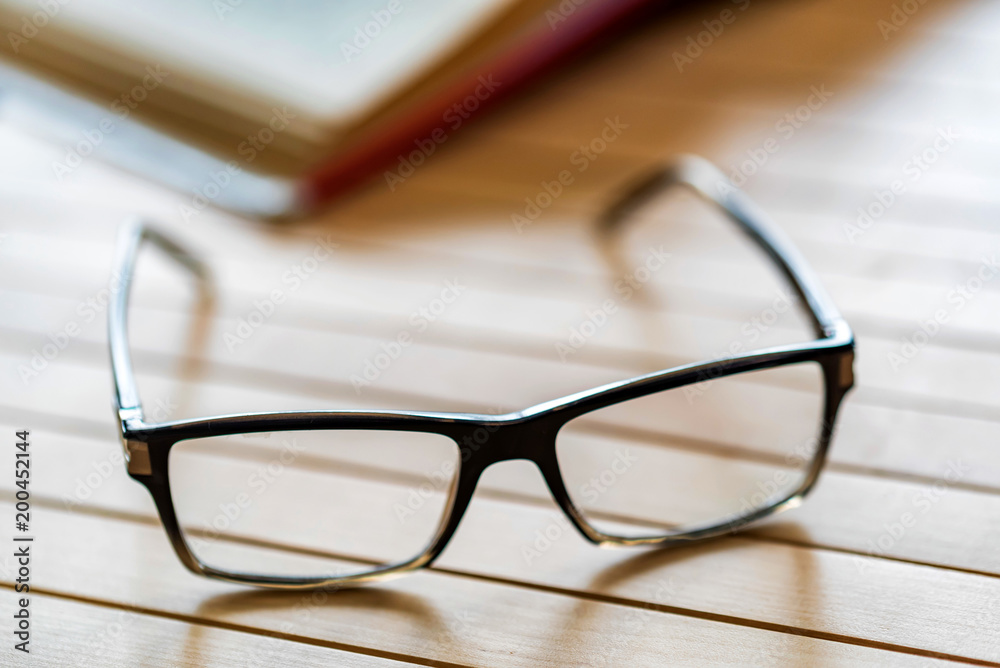 Open book and glasses on wooden table close Open book and glasses on wooden table close