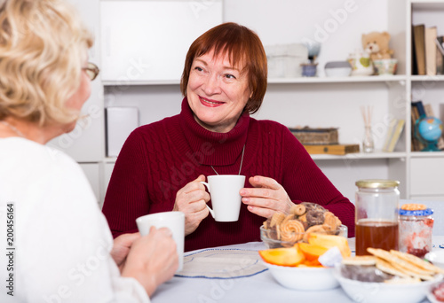 Happy senior woman with female friend over cup of coffee © JackF