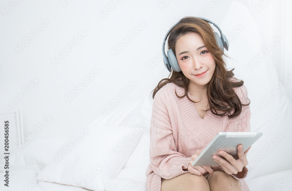 Portrait of young beautiful asian woman relax using smartphone listen to music from headphone Smile happy asian girl online shopping at home, Cheerful relaxing in cold winter concept - obrazy, fototapety, plakaty 