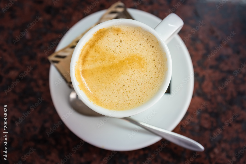 Fototapeta premium Cappuccino or latte milk coffee in white cup and saucer on a marble table