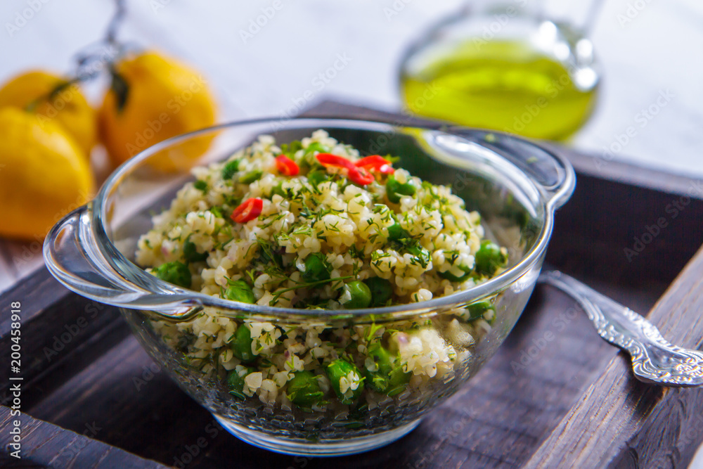 Salad with bulgur and green peas in a glass bowl