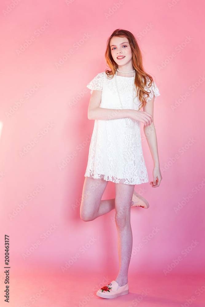 Happy teenage girl smiling. Closeup portrait young happy positive woman wearing white dress standing on pink colourful pastel trendy modern fashion pin-up background. European woman. Positive human em Happy teenage girl smiling. Closeup portrait young happy positive woman wearing white dress standing on pink colourful pastel trendy modern fashion pin-up background. European woman. Positive human em