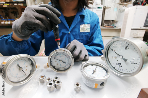 Instrument technician is fixing pressure guages. Engineer check and repair pressure guages on the table.