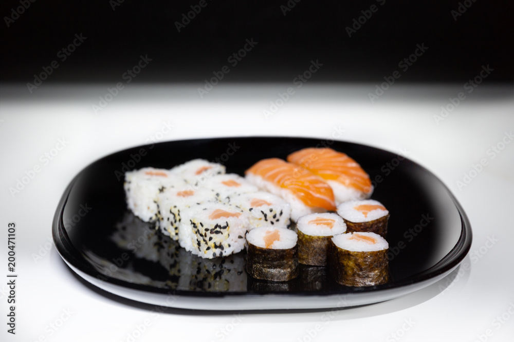 Sushi, Japanese food prepared with a base of rice and various raw fish. Here it is served with a particular and modern style, where the colors of the salmon stand out on the basis of black and white. Sushi, Japanese food prepared with a base of rice and various raw fish. Here it is served with a particular and modern style, where the colors of the salmon stand out on the basis of black and white.