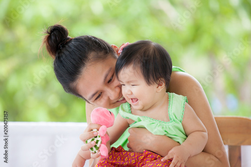 Cute asian baby girl in Thai traditon dress smiling and playing with her mother and turtle doll with love and happiness