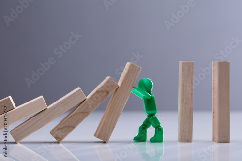 Human Figure Stopping Wooden Dominos Blocks photo