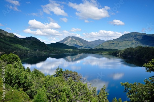 Horizontal photo of lake Machonico in Argentina with water reflection on the foreground and mountains and clouds in the background