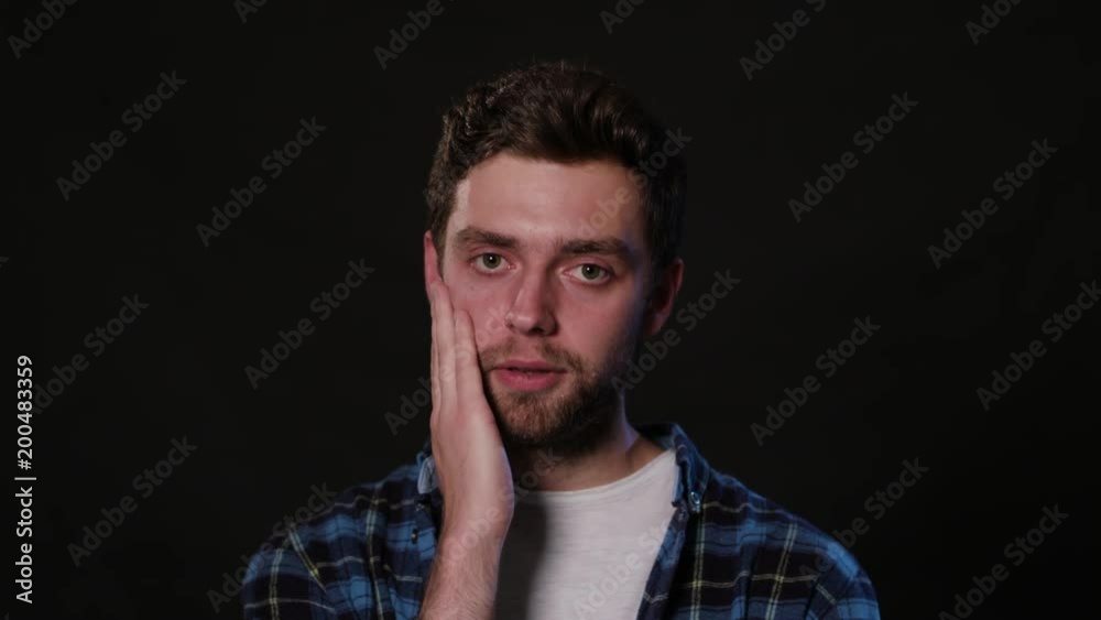 A young man immitating a toothache against a black background. Close-up Shot A young man immitating a toothache against a black background. Close-up Shot