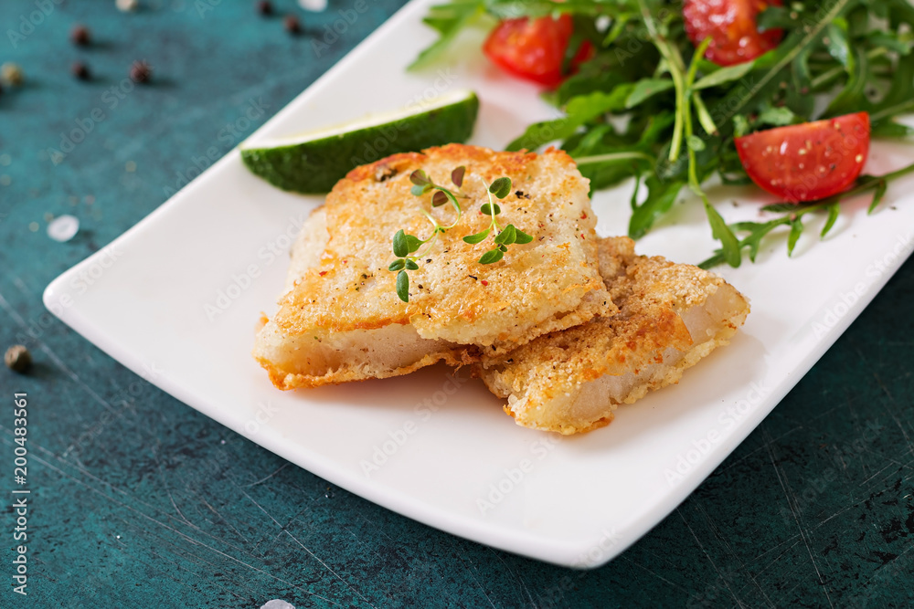 Fried white fish fillets and tomato salad with arugula.