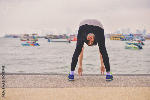 Sports concept. Beautiful girl is exercising on the beach with warm up. Beautiful girl is happy to exercise. photo