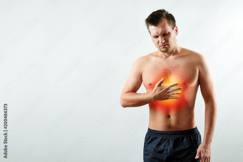 A man holds his hands and region of the heart, chest pain, a pain in the heart highlighted in red, a heart attack. Light background. The concept of medicine, massage, physiotherapy, health. A man holds his hands and region of the heart, chest pain, a pain in the heart highlighted in red, a heart attack. Light background. The concept of medicine, massage, physiotherapy, health.