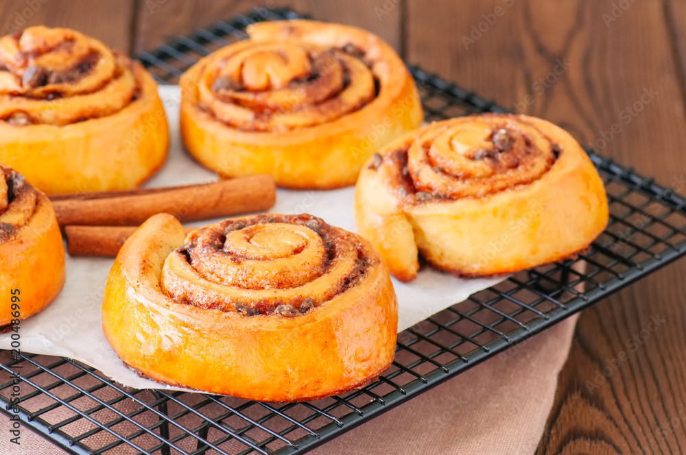 Classic cinnamon rolls - cinnabons won a wire rack. Wooden background. Classic cinnamon rolls - cinnabons won a wire rack. Wooden background.