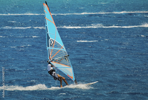 the windsurfer on the board under sail moves at a speed along the surface of the sea,