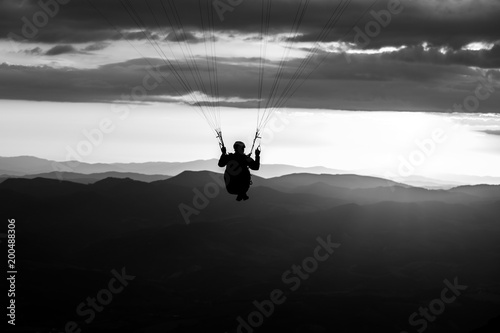 Beautiful shot of a paraglider silhouette flying over Monte Cucco (Umbria, Italy) with sunset on the background