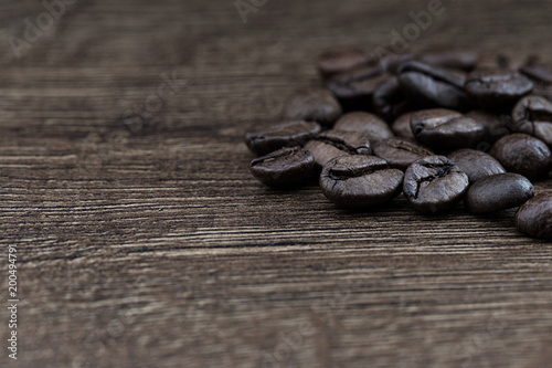 Coffee beans on a dark background and a wooden table. Closeup.