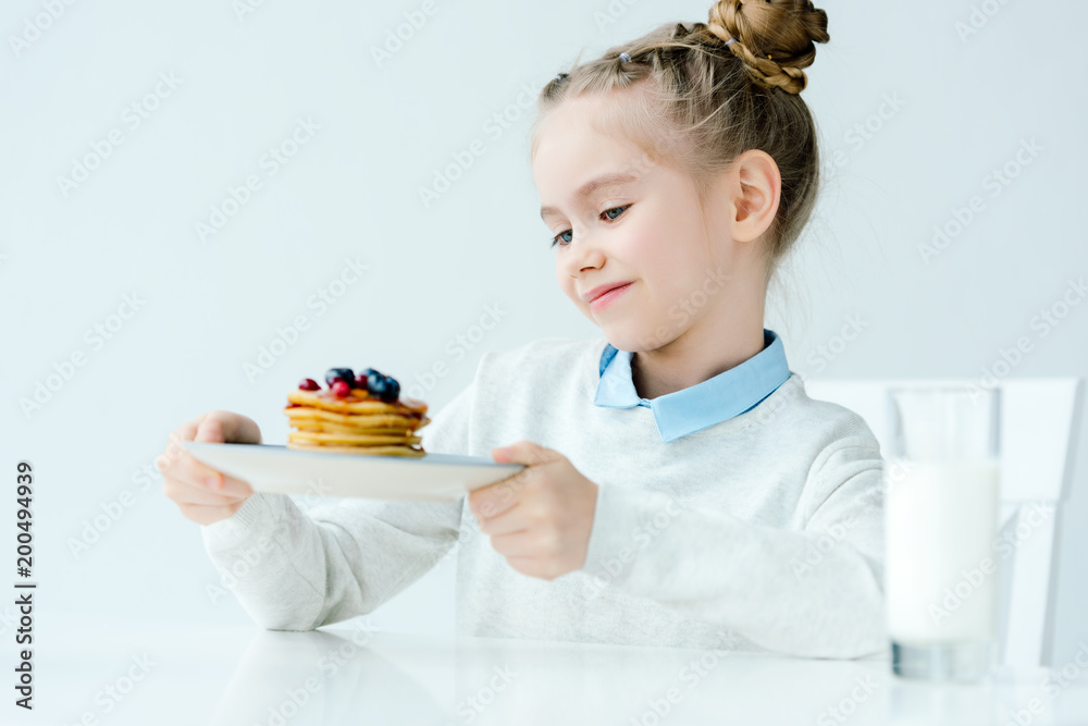 little kid looking at homemade pancakes with berries and honey in hands little kid looking at homemade pancakes with berries and honey in hands