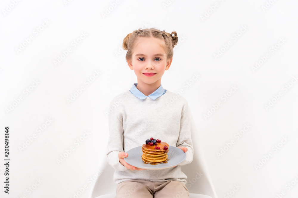 adorable child holding plate with pancakes and looking at camera isolated on white adorable child holding plate with pancakes and looking at camera isolated on white