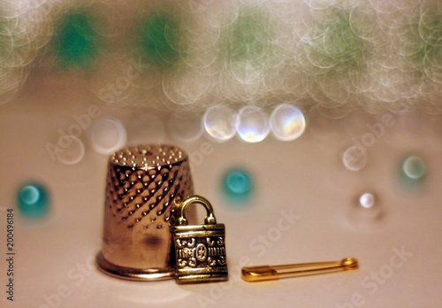 Macro still life with thimble, pin and pendant in the form of a lock photo