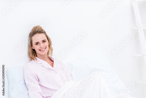 beautiful woman lying in bed in morning and looking at camera
