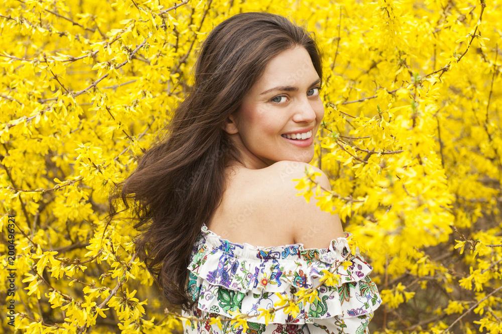 Young woman in the flowered, yellow garden in the spring time Young woman in the flowered, yellow garden in the spring time