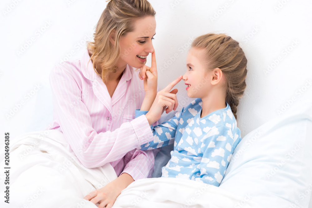 side view of mother and daughter touching noses with fingers at home