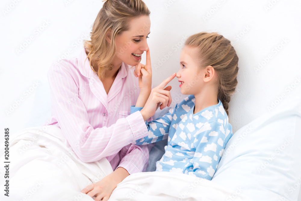 side view of mother and daughter touching noses with fingers at home side view of mother and daughter touching noses with fingers at home