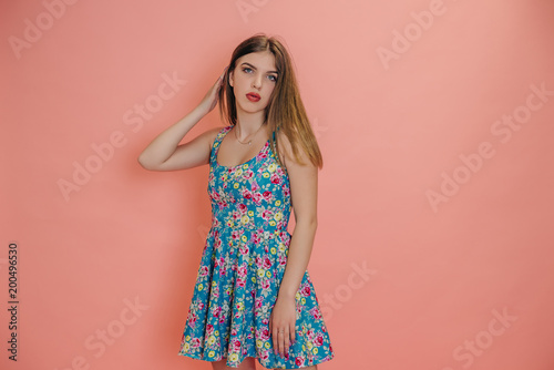 young girl stroking her beautiful hair, on a studio background, in a summer dress