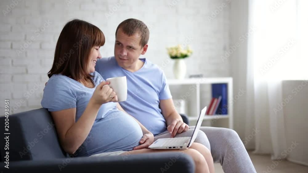 online shopping concept - pregnant woman and her husband with laptop at home online shopping concept - pregnant woman and her husband with laptop at home